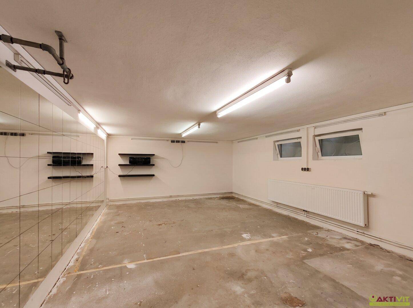 Geräumiger Kellerraum mit Spiegelwand und Fenstern, vielseitig nutzbar.