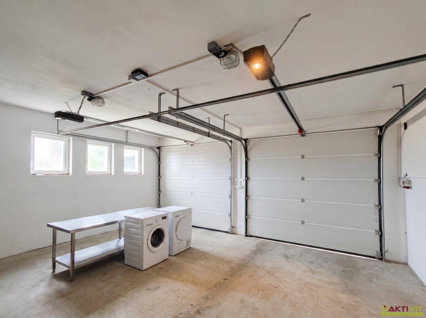 Doppelgarage mit zwei Toren, Fenstern und Waschmaschinen, bietet viel Platz.