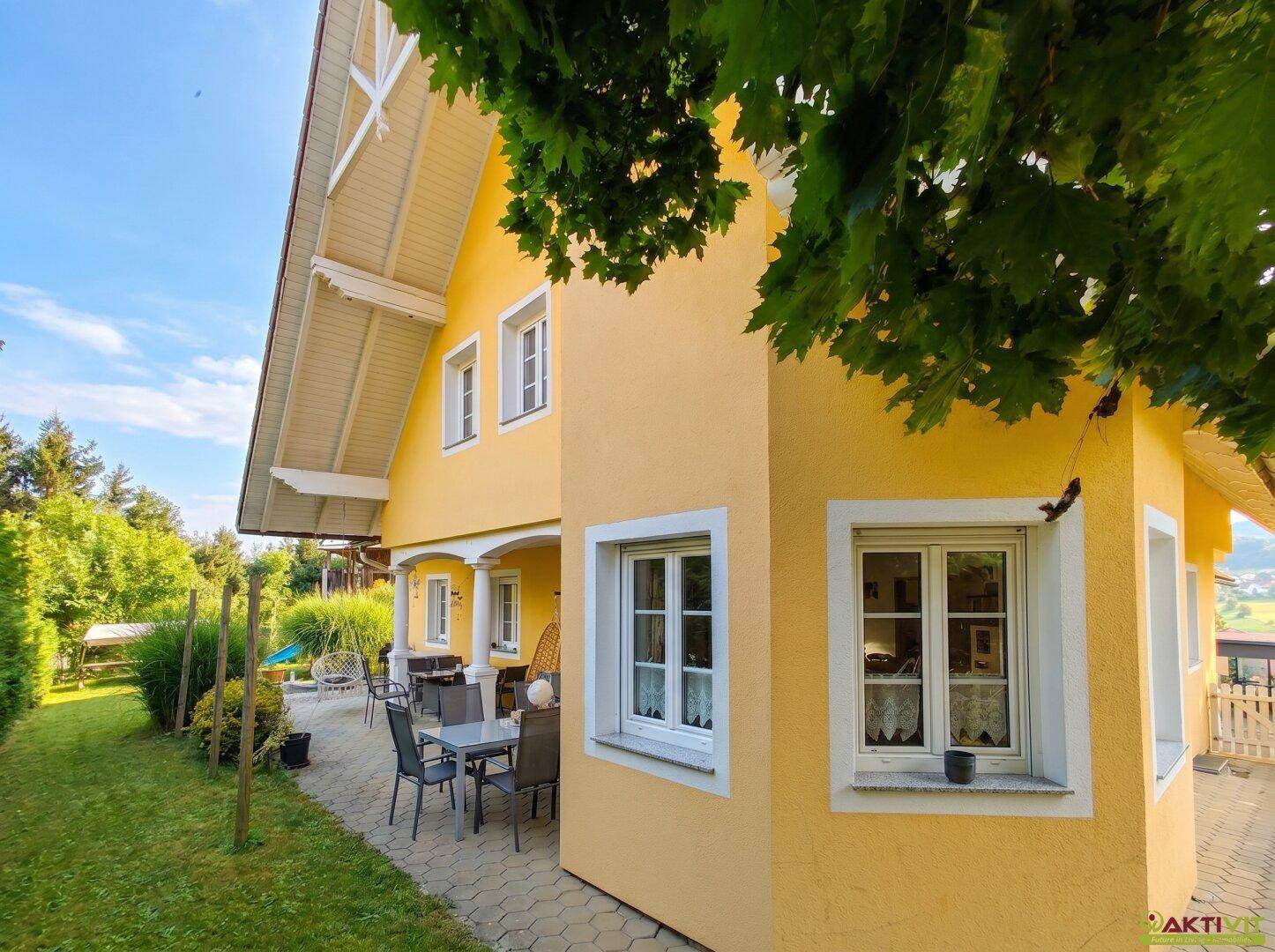 Seitenansicht des Hauses mit Terrasse, Gartenbereich und grüner Umgebung.