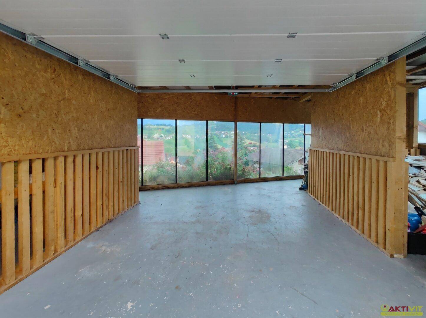 Geräumiger Innenraum der Garage mit großen Fenstern und Blick auf die umliegende Landschaft.