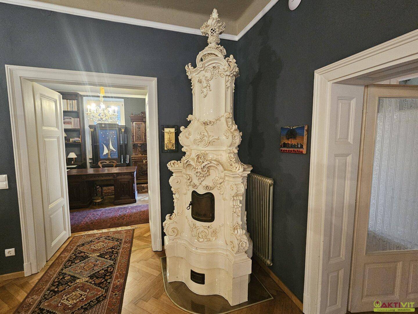 Prunkvoller Kachelofen in einem eleganten Wohnzimmer mit dunklen Wänden und Blick in ein Arbeitszimmer.