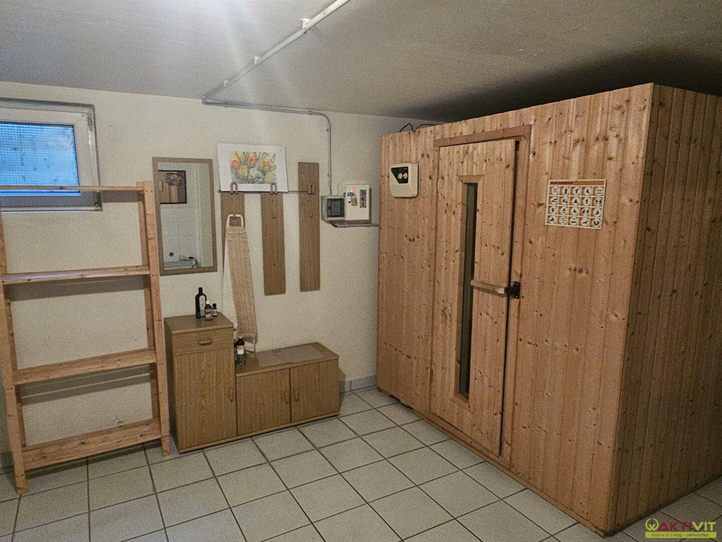 Funktionaler Raum im Untergeschoss mit einer Holzsauna, Fliesenboden und kleinem Fenster.