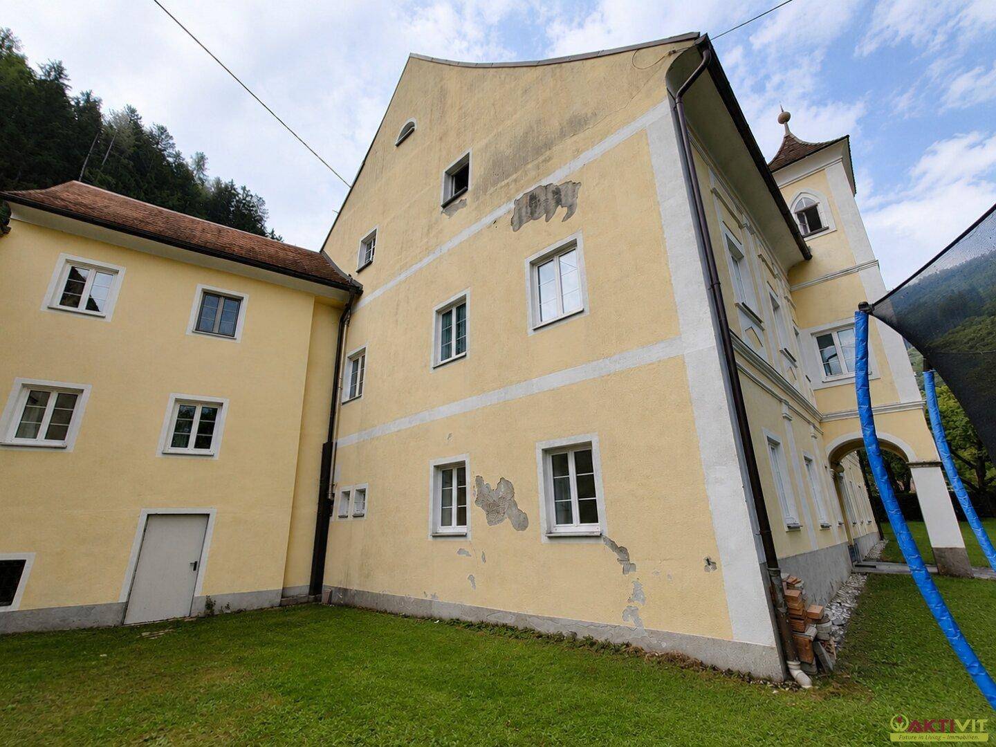 Seitenansicht des historischen Gebäudes mit gelber Fassade und angrenzendem Anbau.
