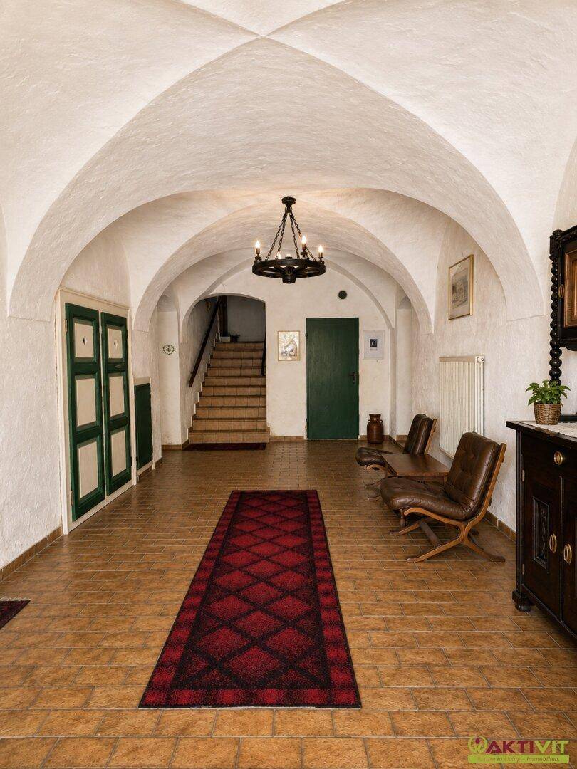 Historischer Flur mit Kreuzgewölbe, Terrakottaboden und traditionellen Holzmöbeln.