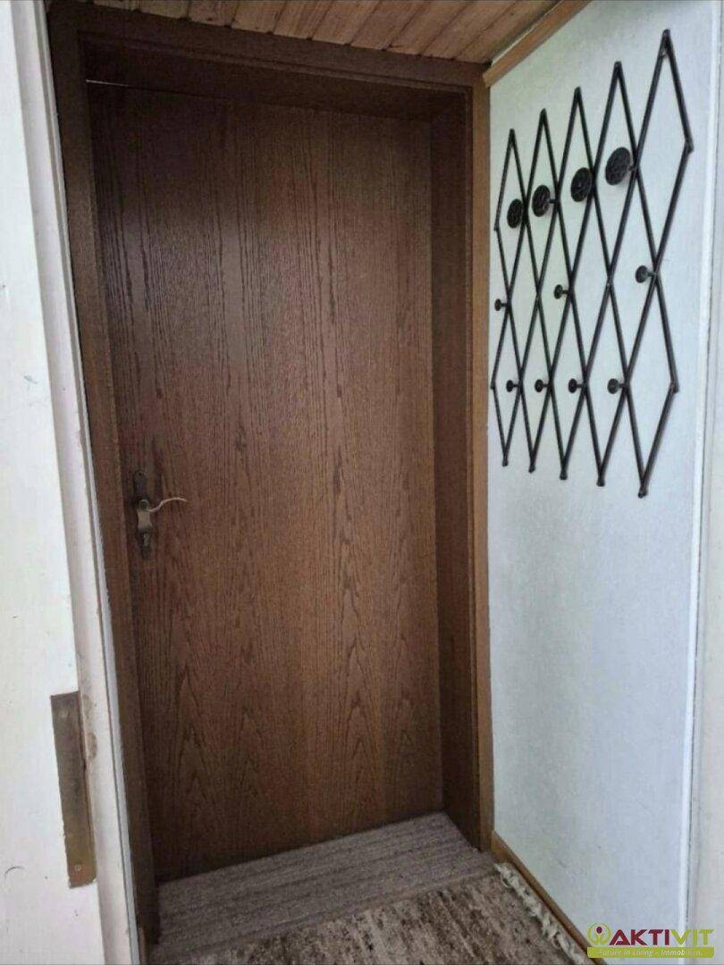 Holztür mit traditioneller Garderobe in einem schlichten Eingangsbereich.