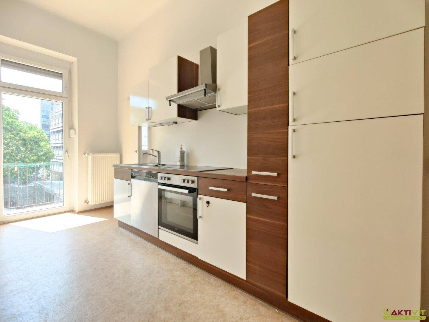 Moderne Einbauküche mit weißen und holzfarbenen Fronten, ausgestattet mit Backofen und Kochfeld.