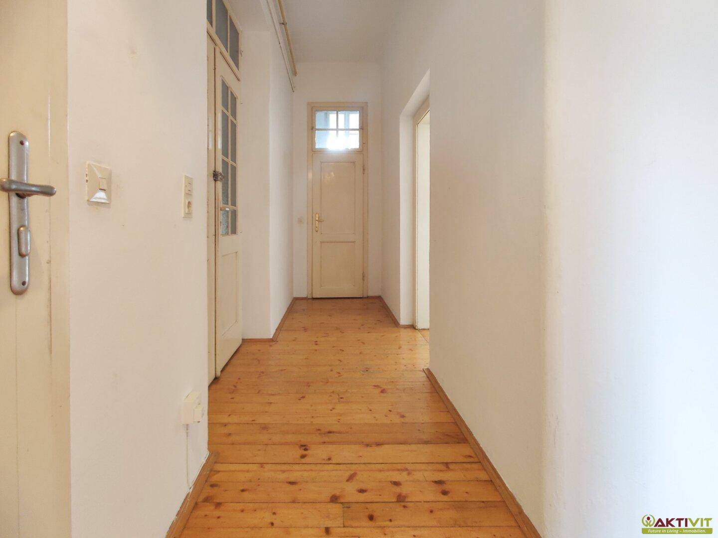 Langer, heller Flur mit Holzdielenboden, der verschiedene Zimmer der Wohnung verbindet.