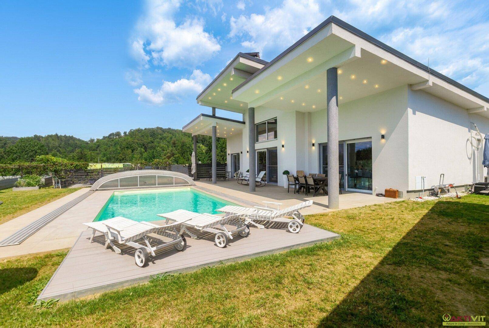 Luxuriöse Villa mit großem Poolbereich, Sonnenliegen und überdachter Terrasse.