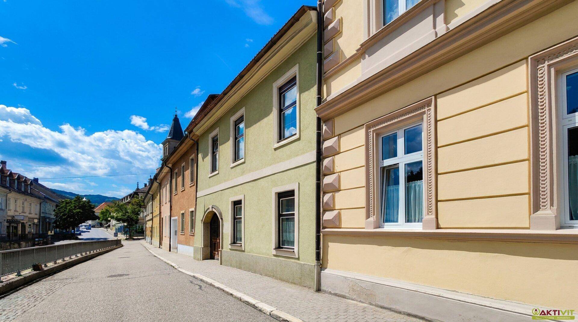 Historische Gebäude entlang einer malerischen Straße unter blauem Himmel mit Wolken.