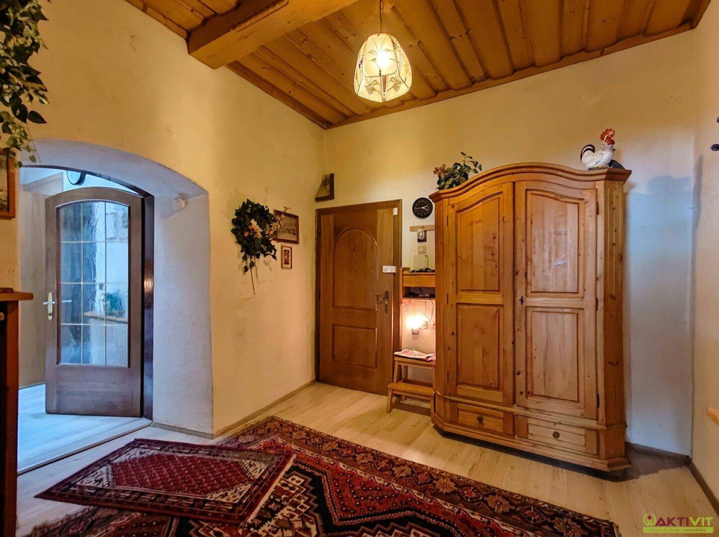 Eingangsbereich mit traditionellen Holzmöbeln, Teppich und gewölbter Decke.