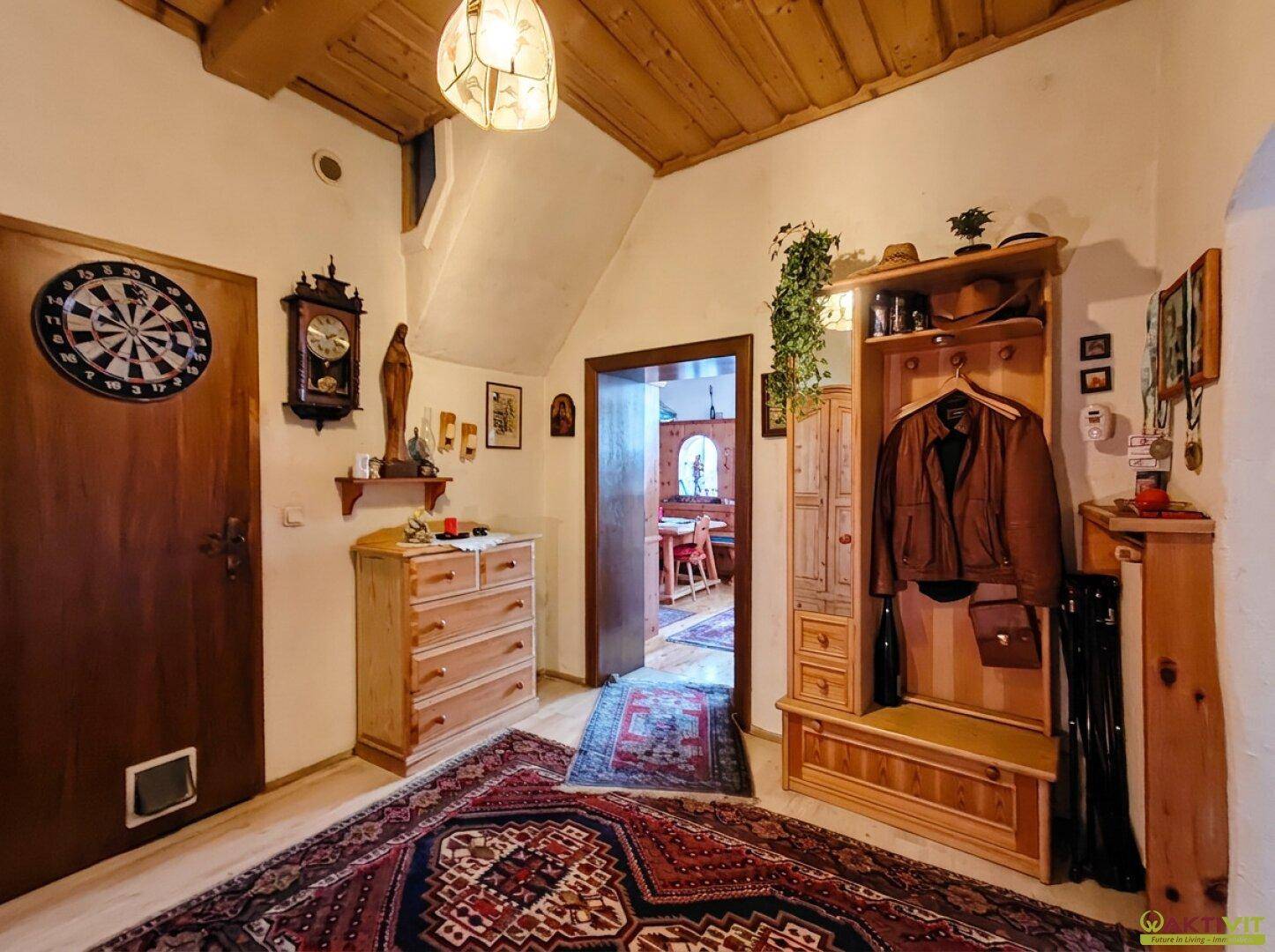 Flur mit traditionellen Holzmöbeln, Teppich und einer Dartscheibe an der Wand.