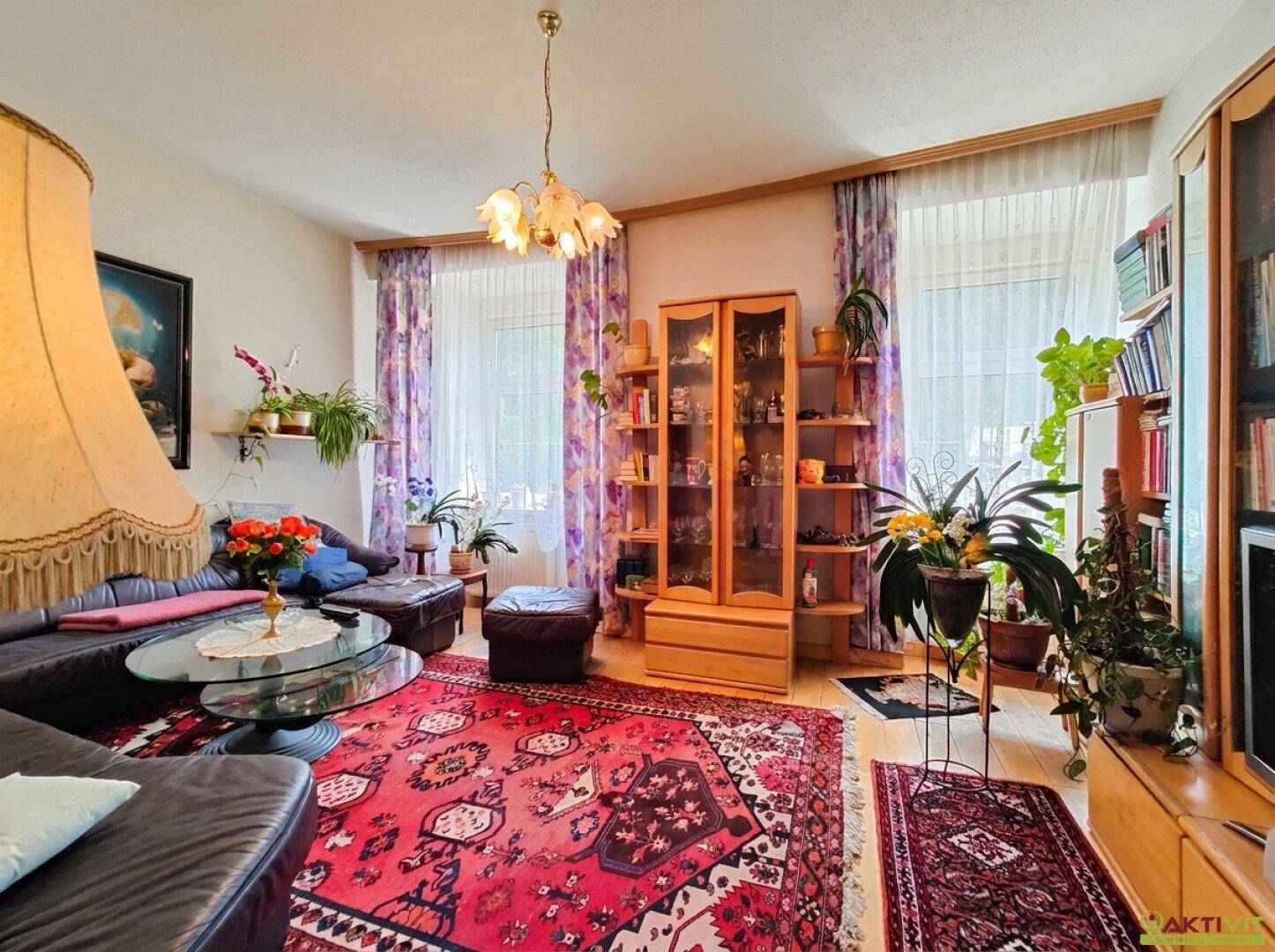 Geräumiges Wohnzimmer mit großem Sofa, vielen Pflanzen und traditioneller Einrichtung.