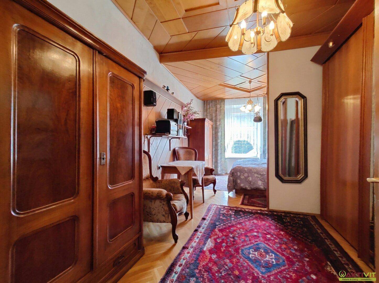 Flur mit Holzdecke und traditionellen Holzschränken, der zu einem Schlafzimmer führt.