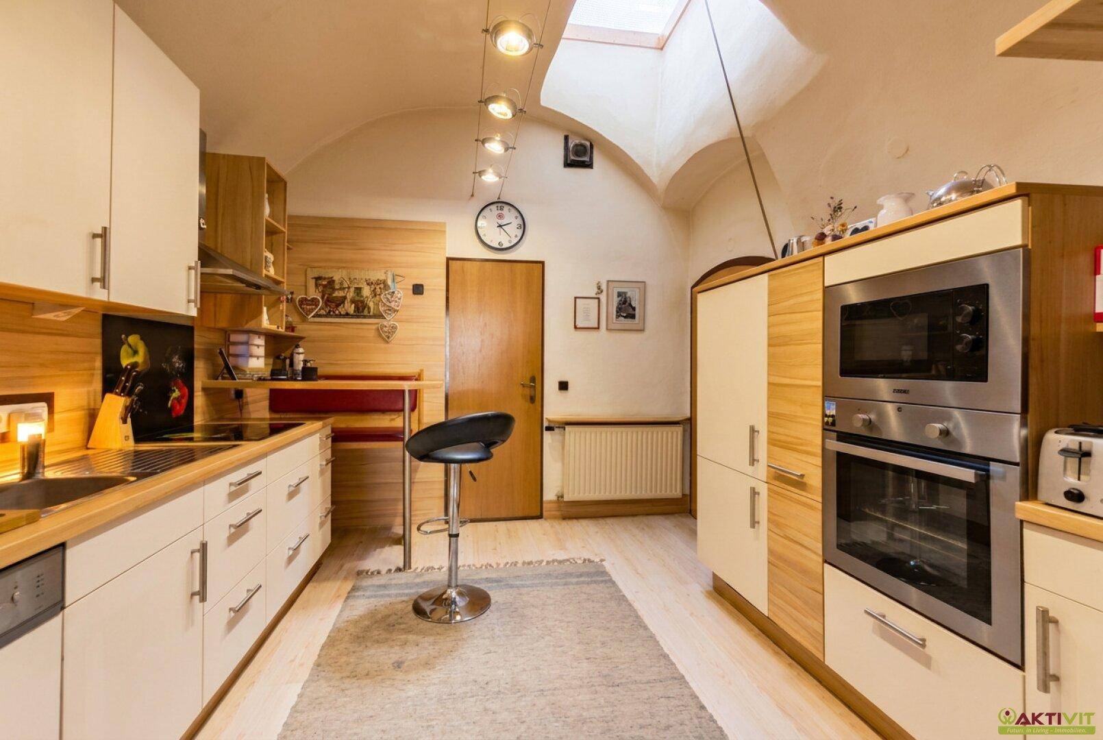 Helle Küche mit gewölbter Decke, Holzfronten, modernen Geräten und Dachfenster.