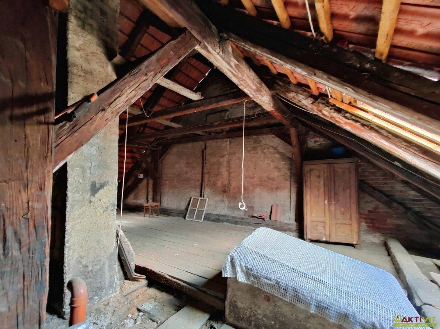 Unausgebauter Dachboden mit sichtbaren Holzbalken und altem Holzfußboden.
