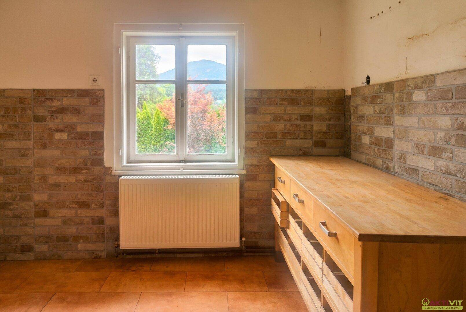 Küche mit Holzarbeitsplatte, Ziegelwandfliesen und Fenster mit Bergblick.