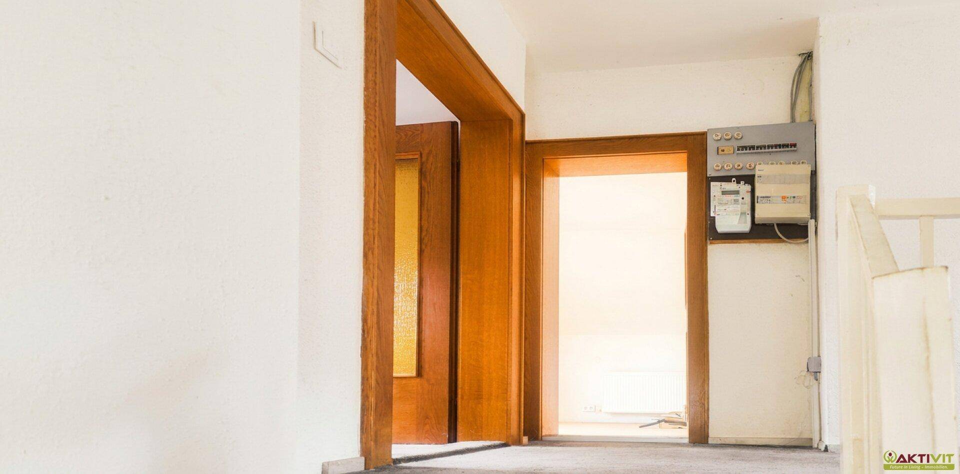 Flur mit Holztüren und einem Sicherungskasten an der Wand.