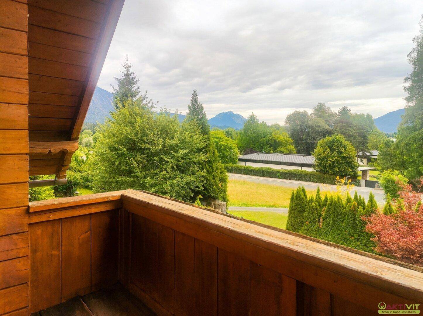 Holzbalkon mit weitem Blick auf die grüne Landschaft und Berge.