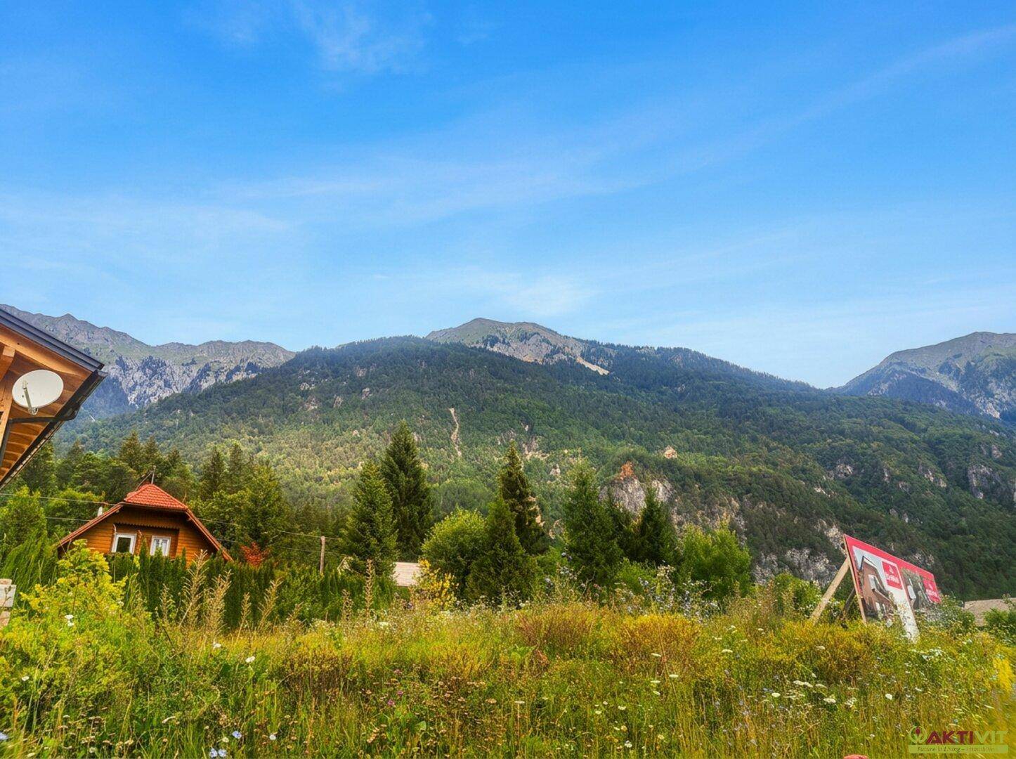 Malerische Landschaft mit Bergen, einem kleinen Haus und einem Werbeplakat am Straßenrand.
