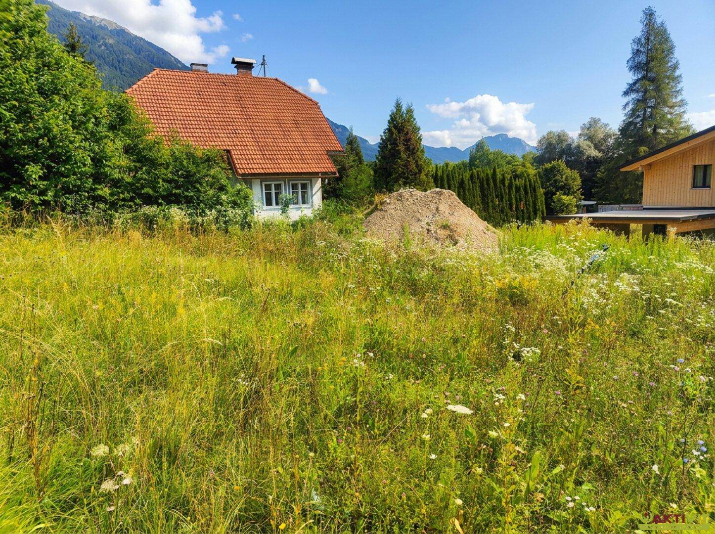 Älteres Haus mit rotem Ziegeldach, umgeben von einer wilden Wiese und einem Erdhaufen.