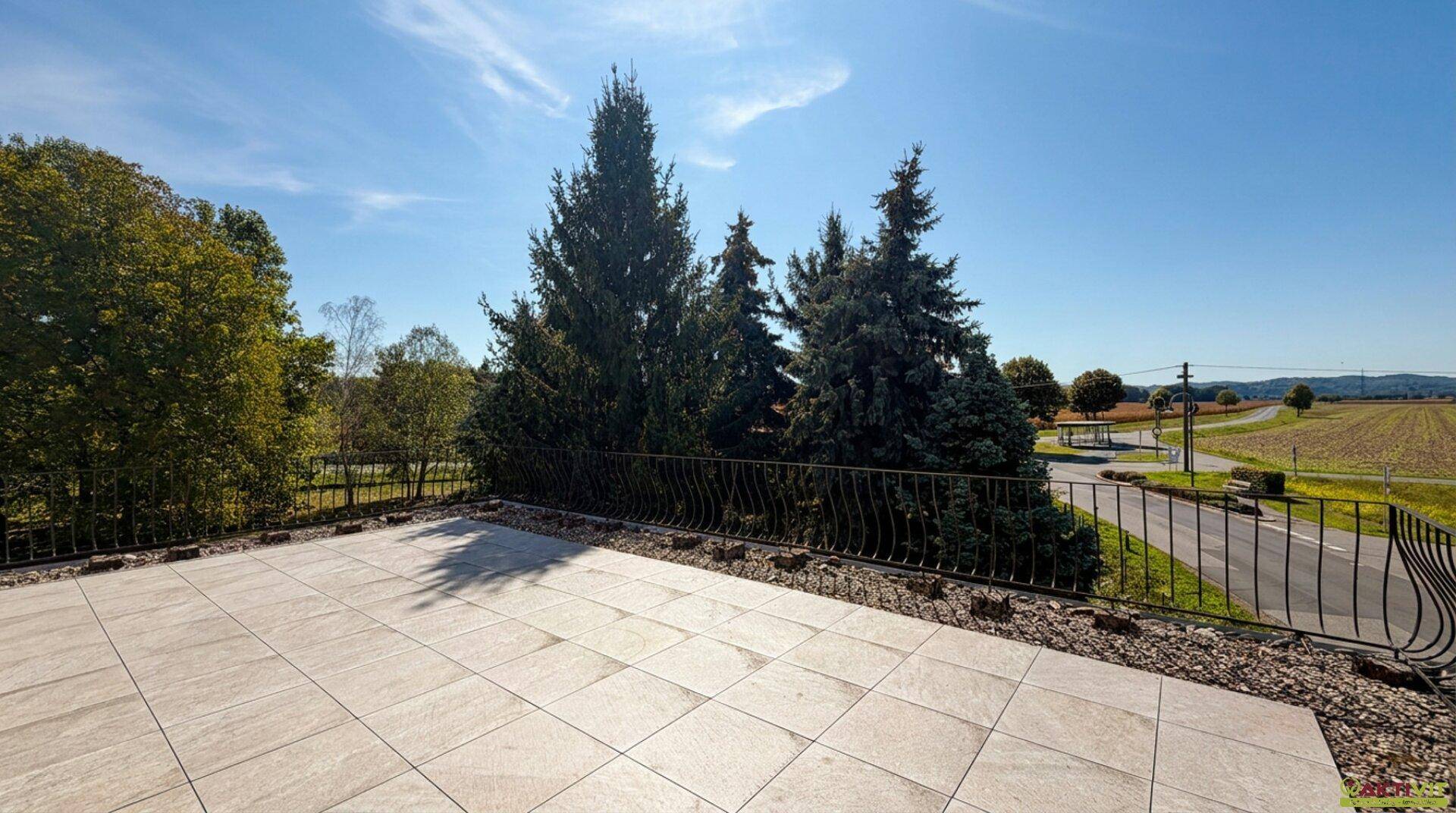 Große geflieste Terrasse mit schmiedeeisernem Geländer und weitem Blick über die Landschaft.
