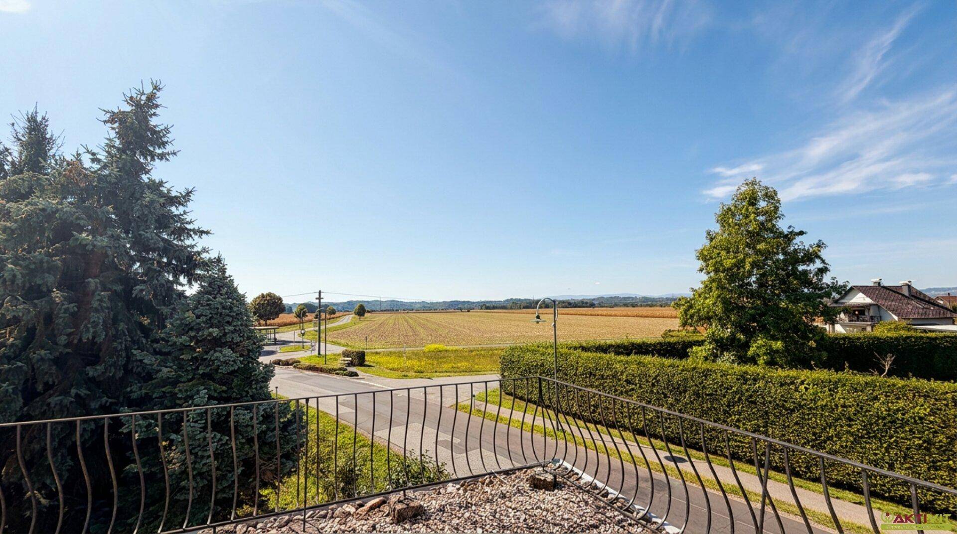 Panoramablick von der Terrasse über weite Felder, eine Landstraße und die ländliche Umgebung.