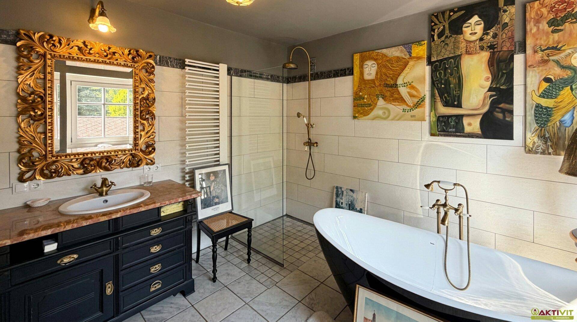 Elegantes Badezimmer mit freistehender Badewanne, Dusche und goldenem Spiegel.