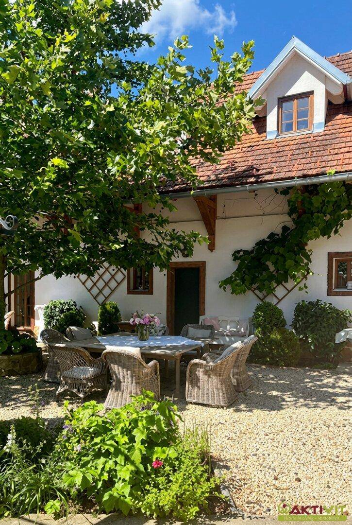 Idyllischer Sitzbereich im Garten unter einem Baum mit Blick auf das charmante Haus.