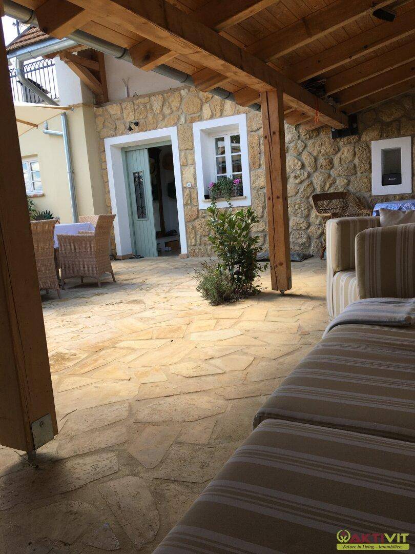 Große gepflasterte Terrasse mit bequemen Loungemöbeln und Steinmauer.