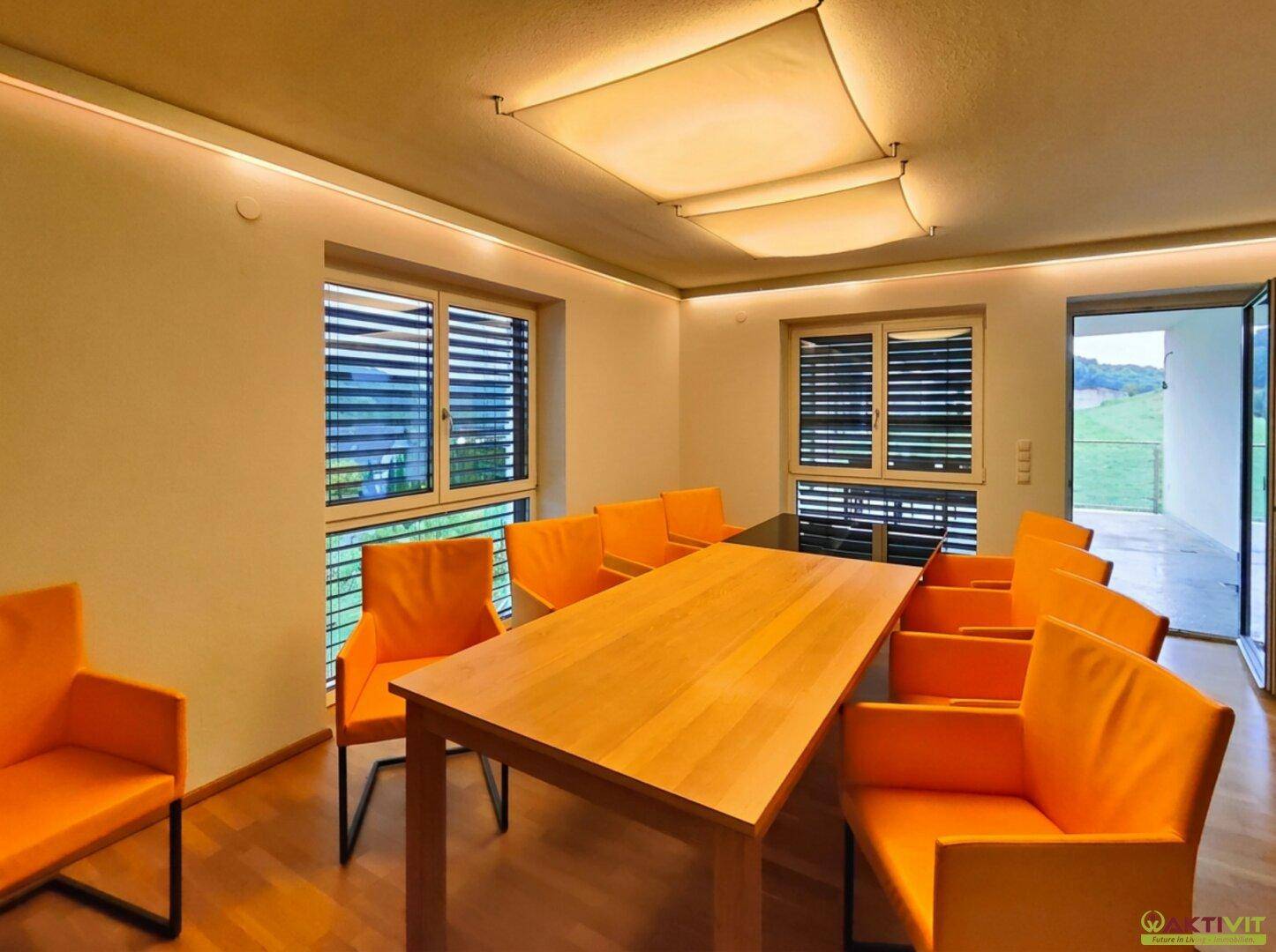 Geräumiger Essbereich mit Holztisch, modernen orangefarbenen Stühlen und Blick ins Grüne.