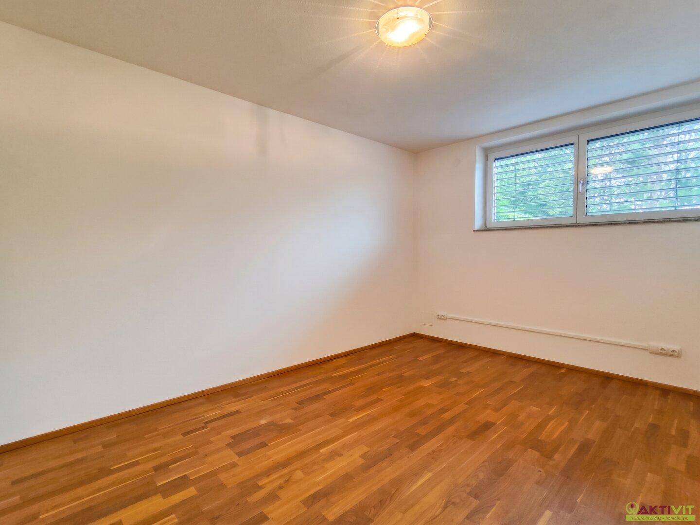 Helles Schlafzimmer mit Holzboden und großem Fenster, bereit zur individuellen Einrichtung.