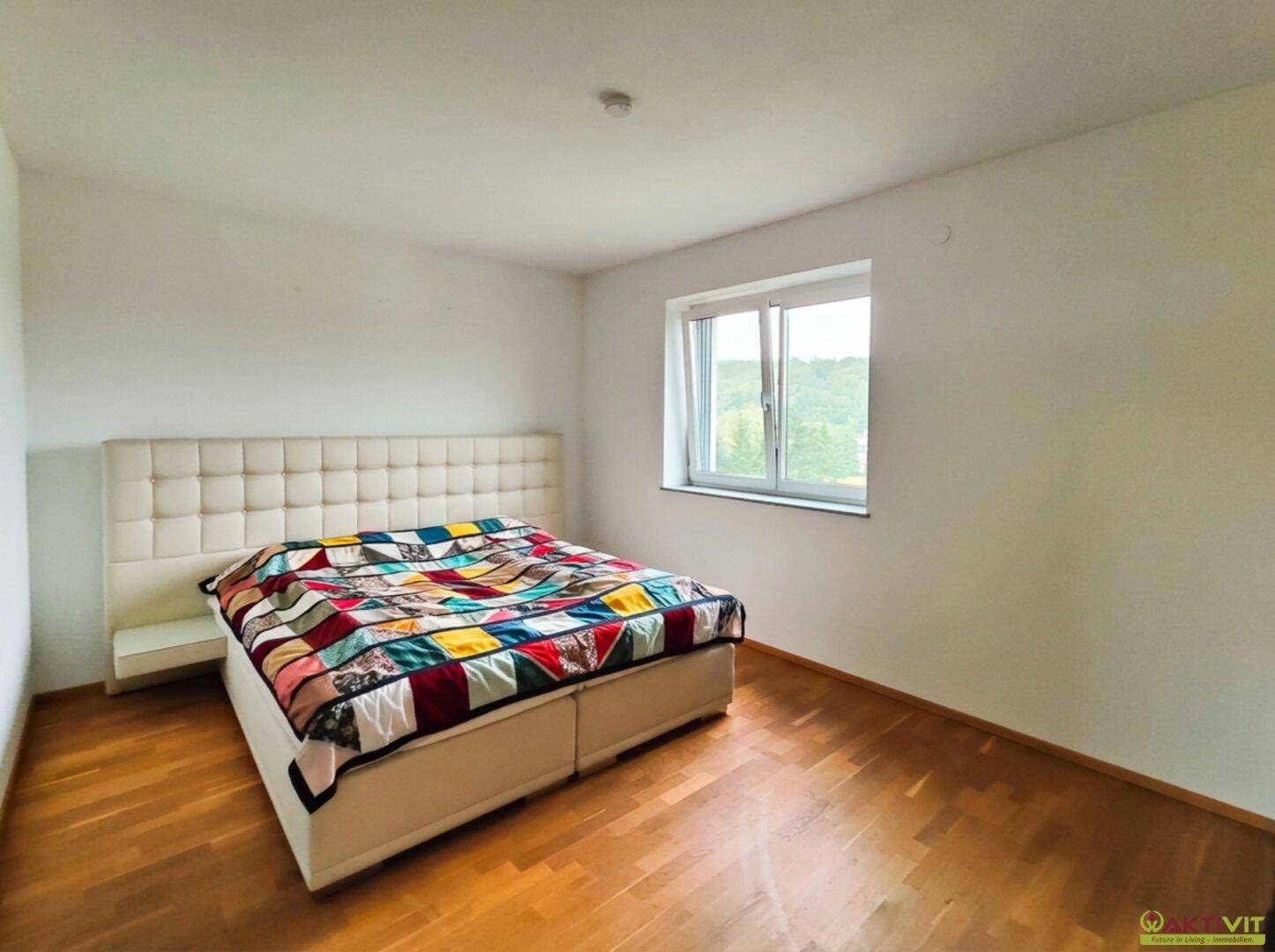 Geräumiges Schlafzimmer mit Holzboden, großem Bett und Fenster mit weitem Ausblick.