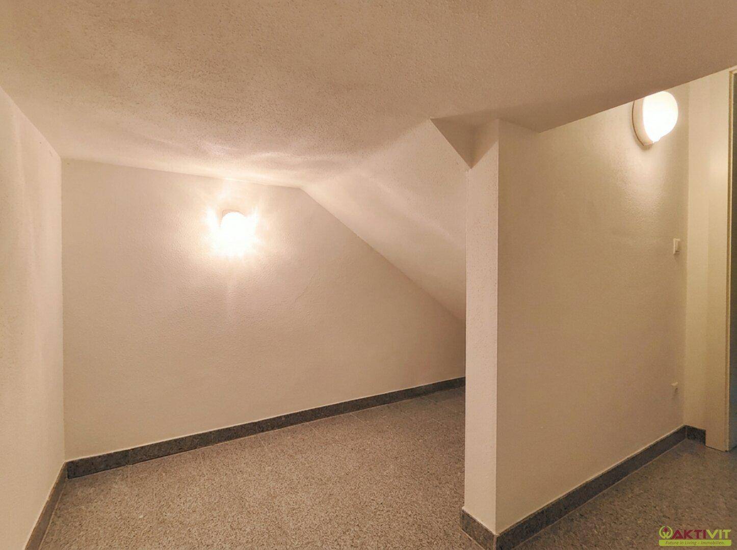 Kellerraum mit schrägen Wänden und robustem Boden, ideal als Abstellfläche.