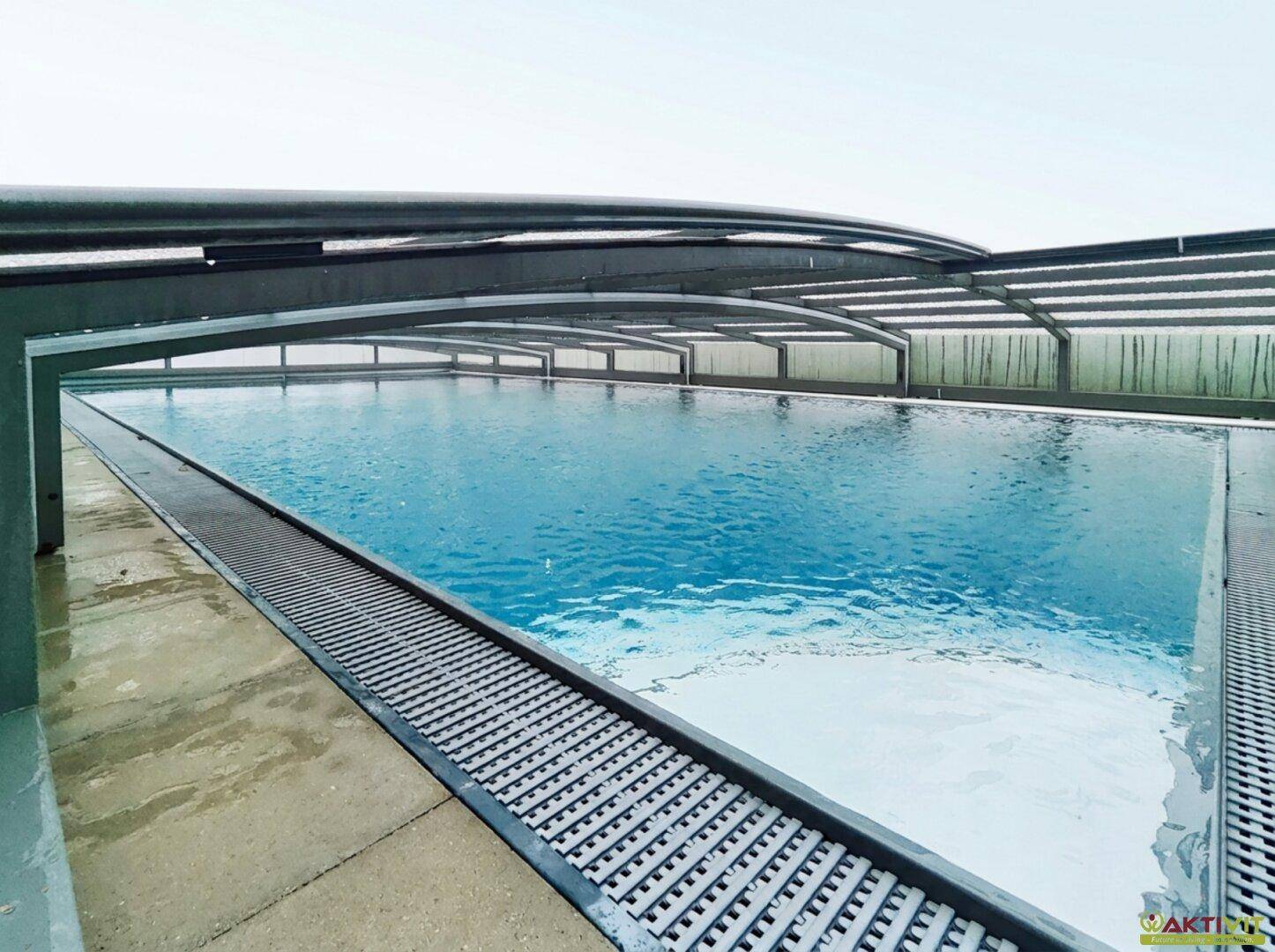 Nahaufnahme des Swimmingpools unter seiner transparenten Abdeckung mit blauem Wasser.