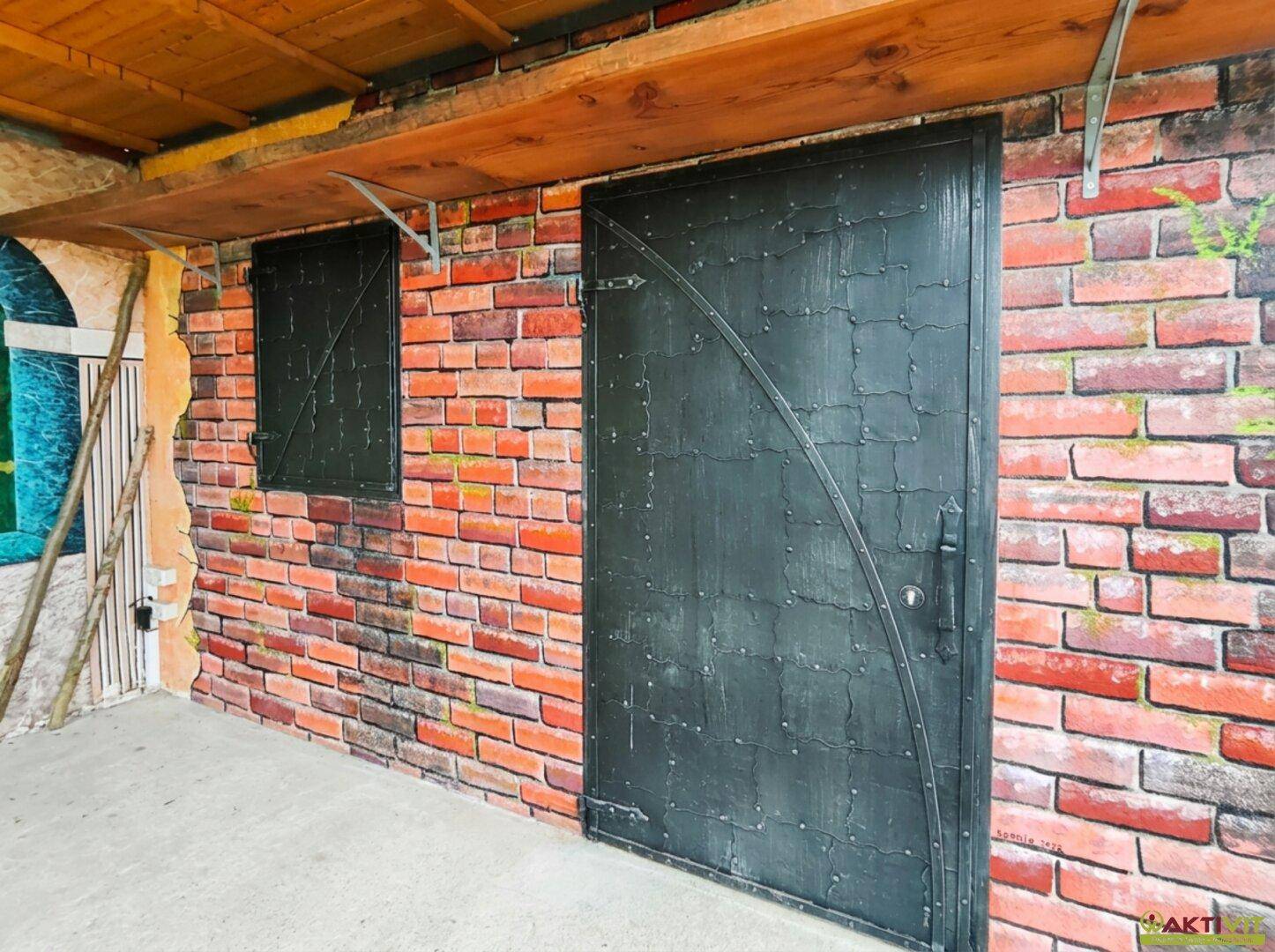 Detailansicht einer dekorativen Ziegelwand mit einer dunklen, verzierten Tür und Fenster.