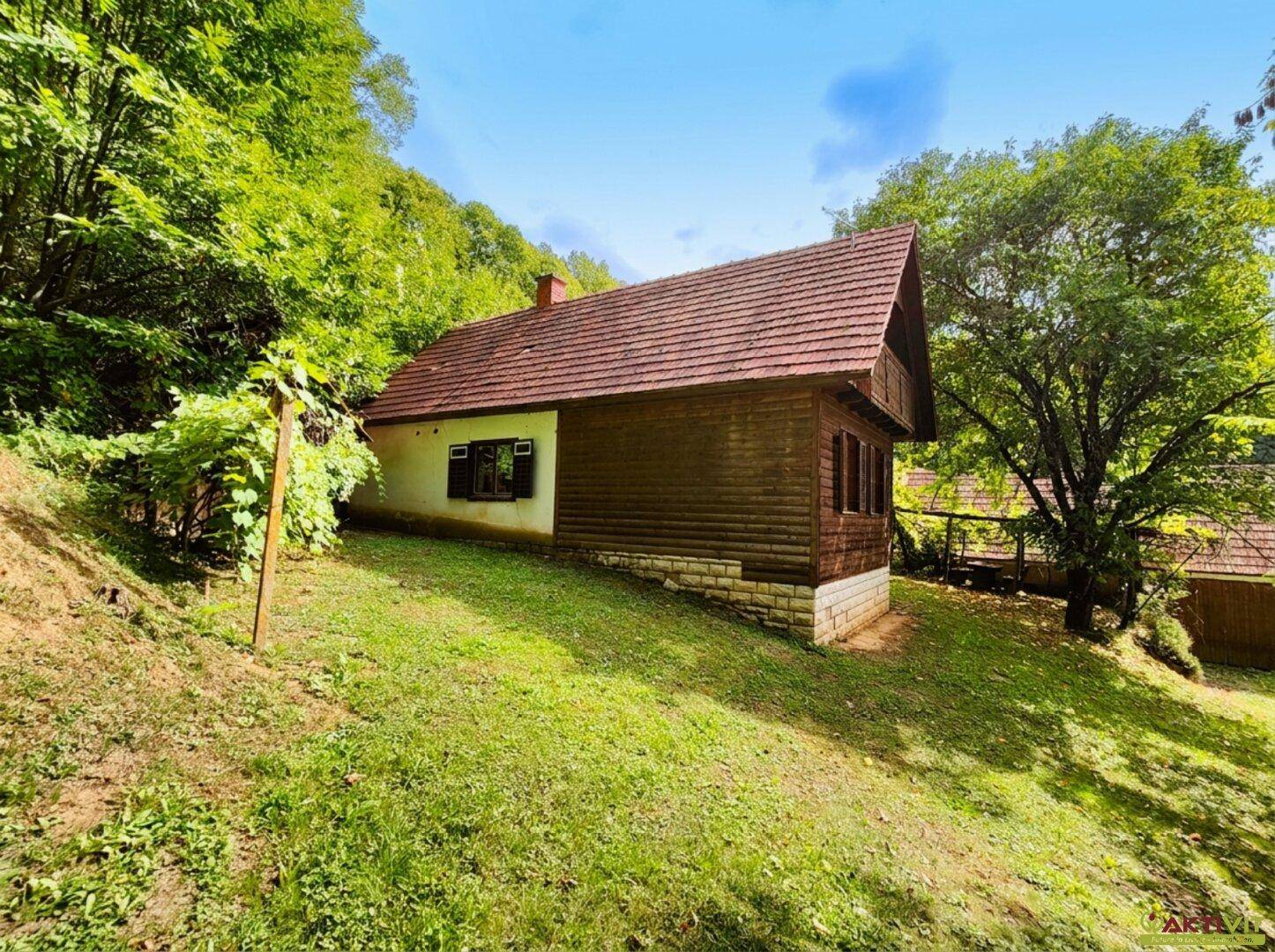 Traditionelles Haus mit Holzelementen und Ziegeldach, eingebettet in eine grüne Hanglandschaft.
