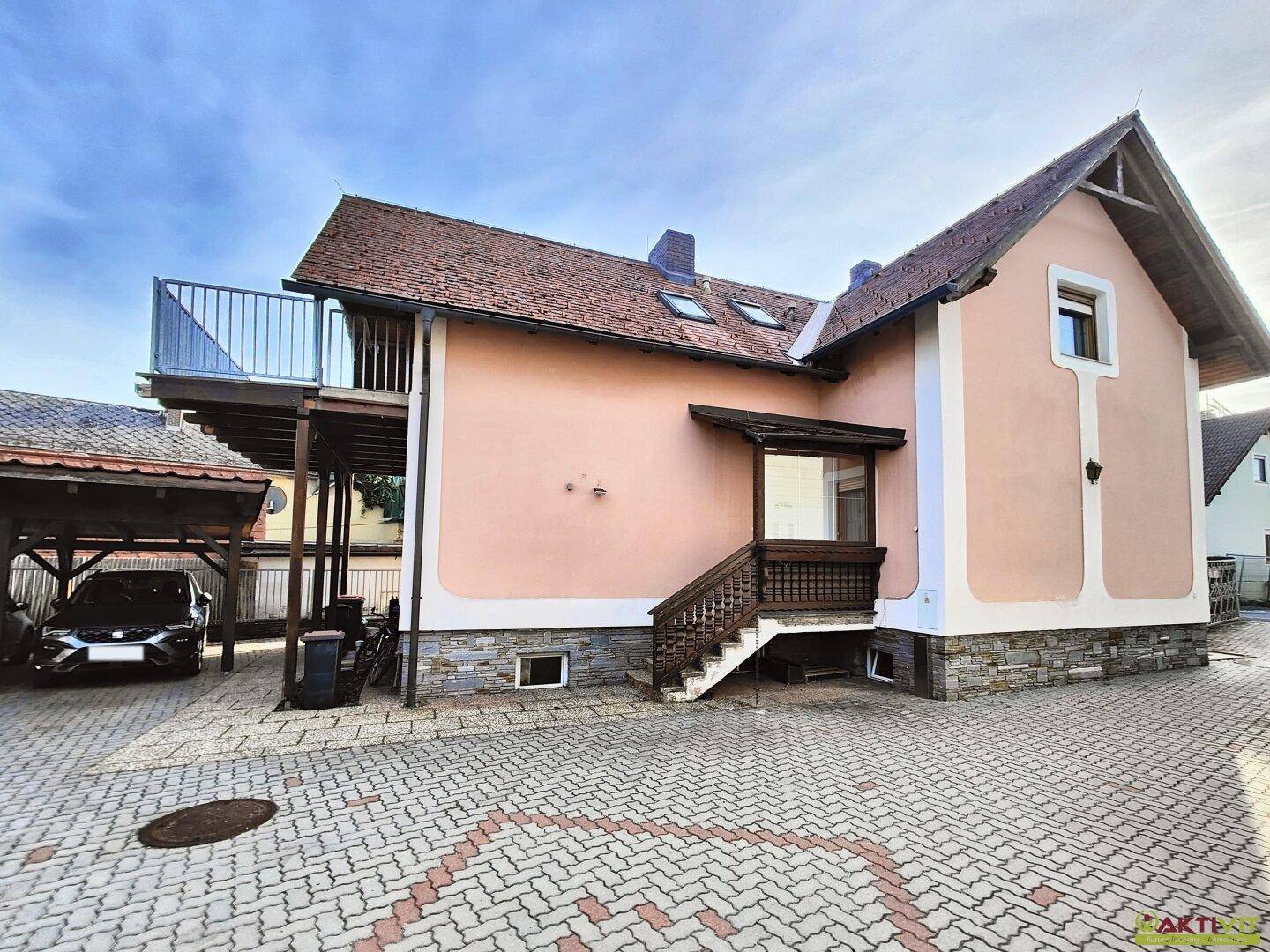 Ansicht des Hauses mit Carport und Außentreppe, die zum oberen Balkon führt.