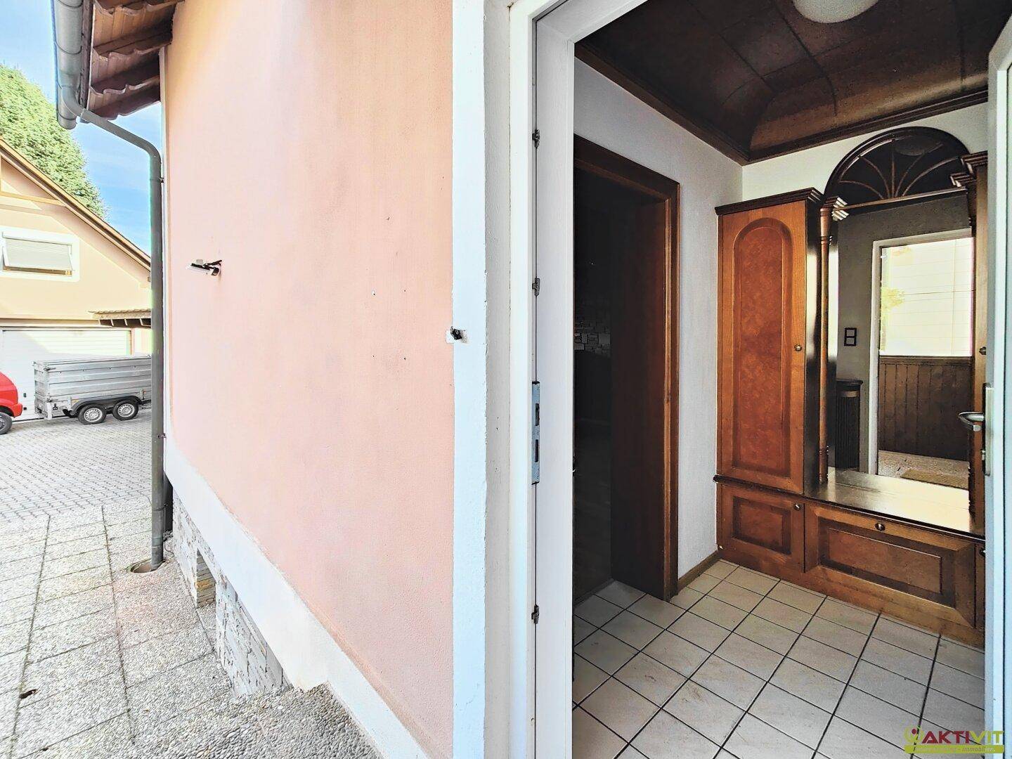 Eingangsbereich mit Fliesenboden und traditioneller Holzgarderobe, die zum Haus führt.