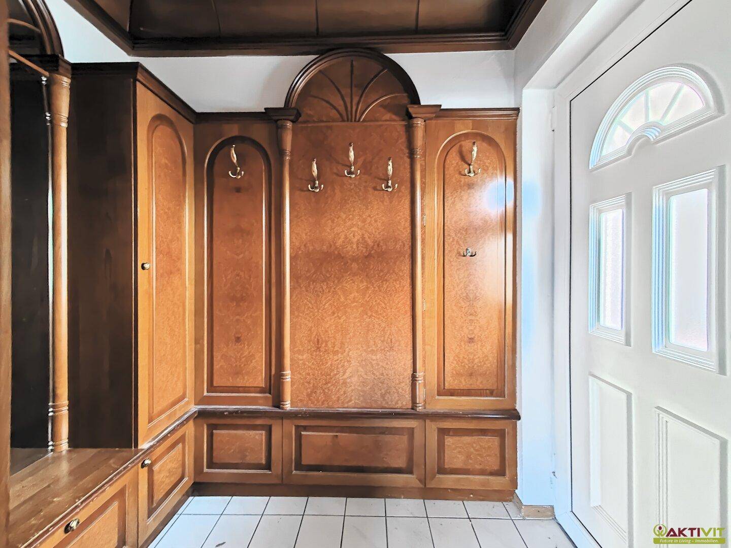 Eingangsbereich mit maßgefertigter Holzgarderobe und Fliesenboden, sehr gepflegt.