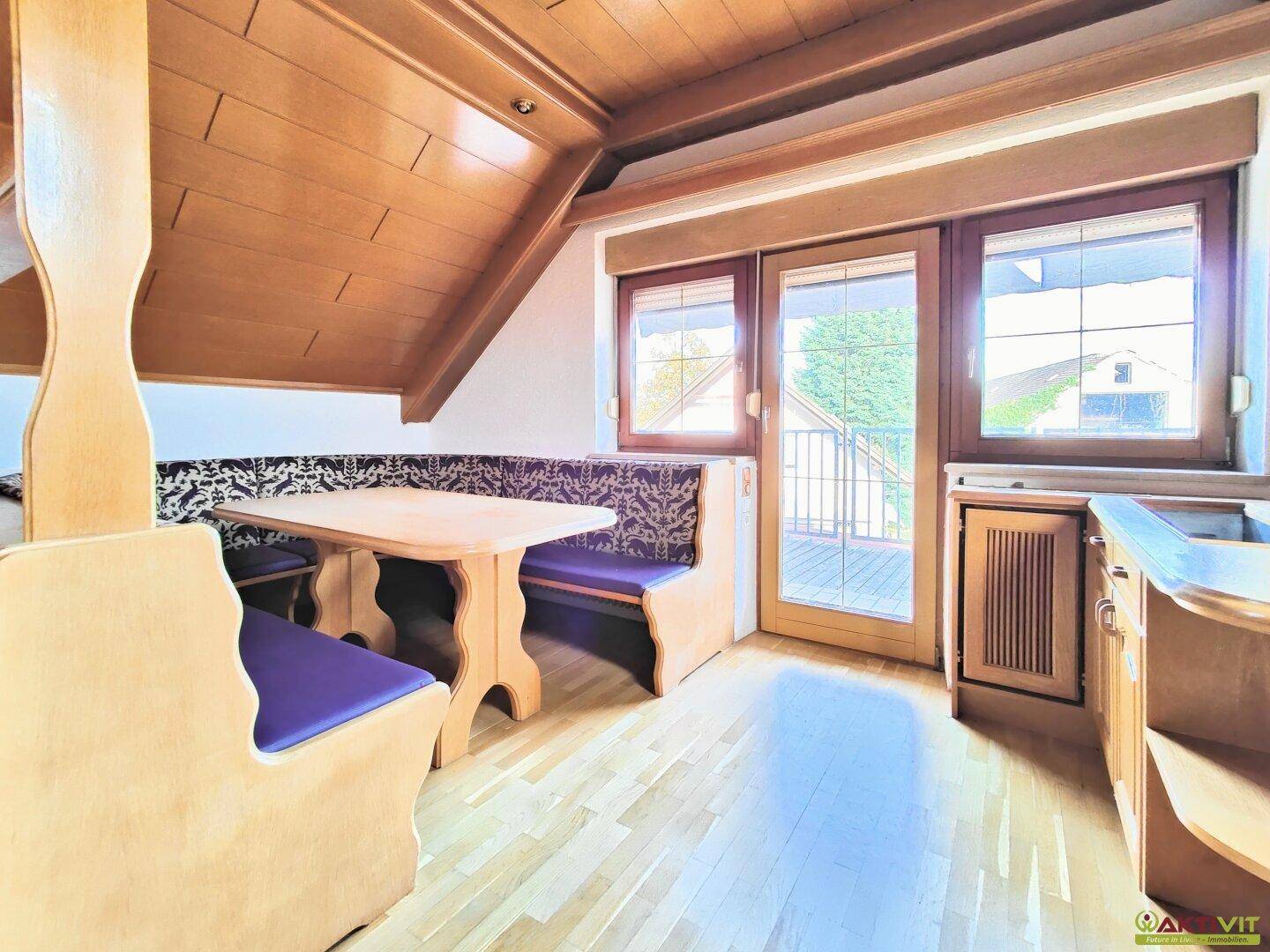 Gemütlicher Essbereich mit Holzbänken, Holzboden und Zugang zu einem Balkon.
