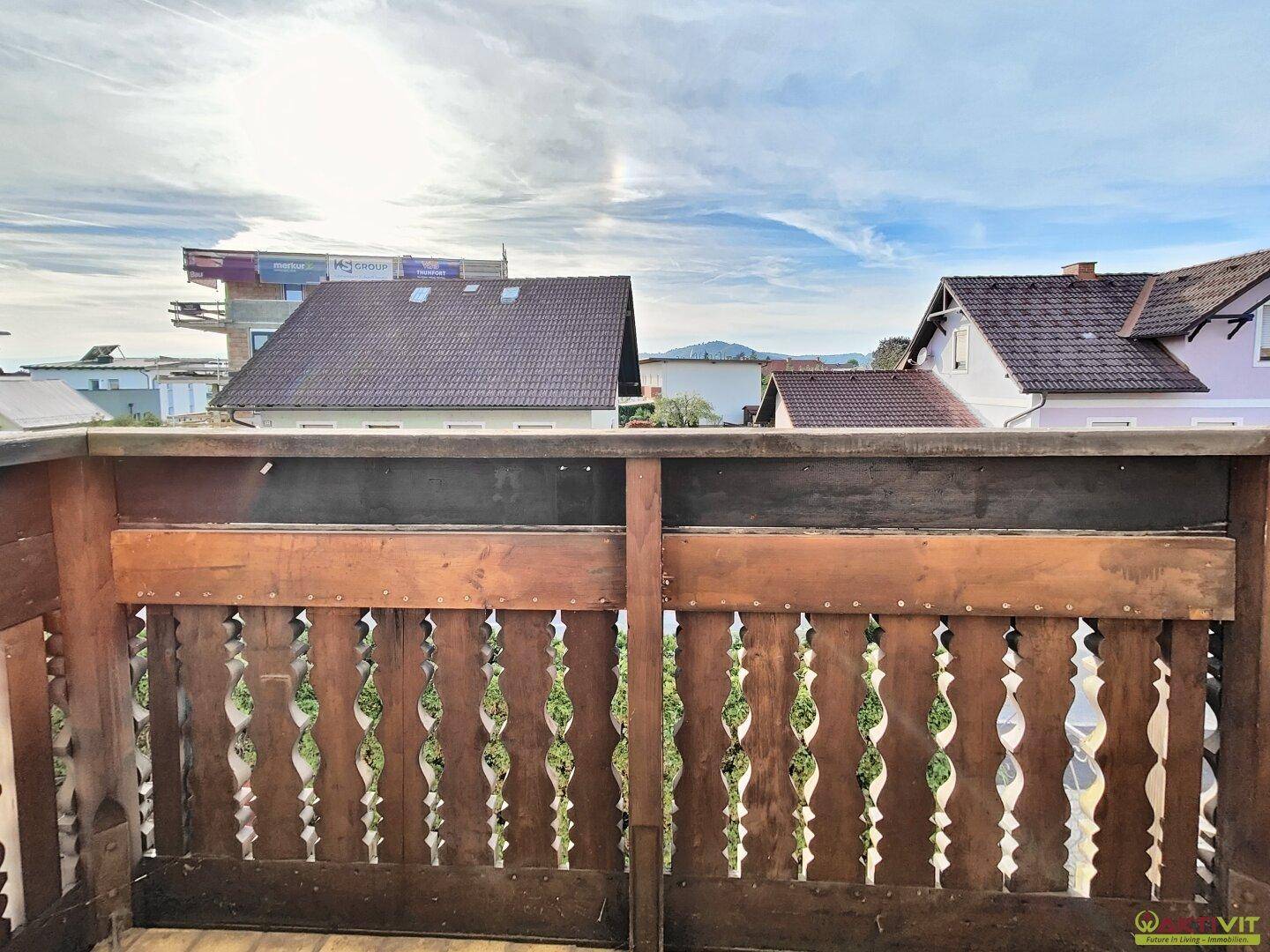 Balkon mit traditionellem Holzgeländer und weitem Blick auf die Umgebung und Berge.