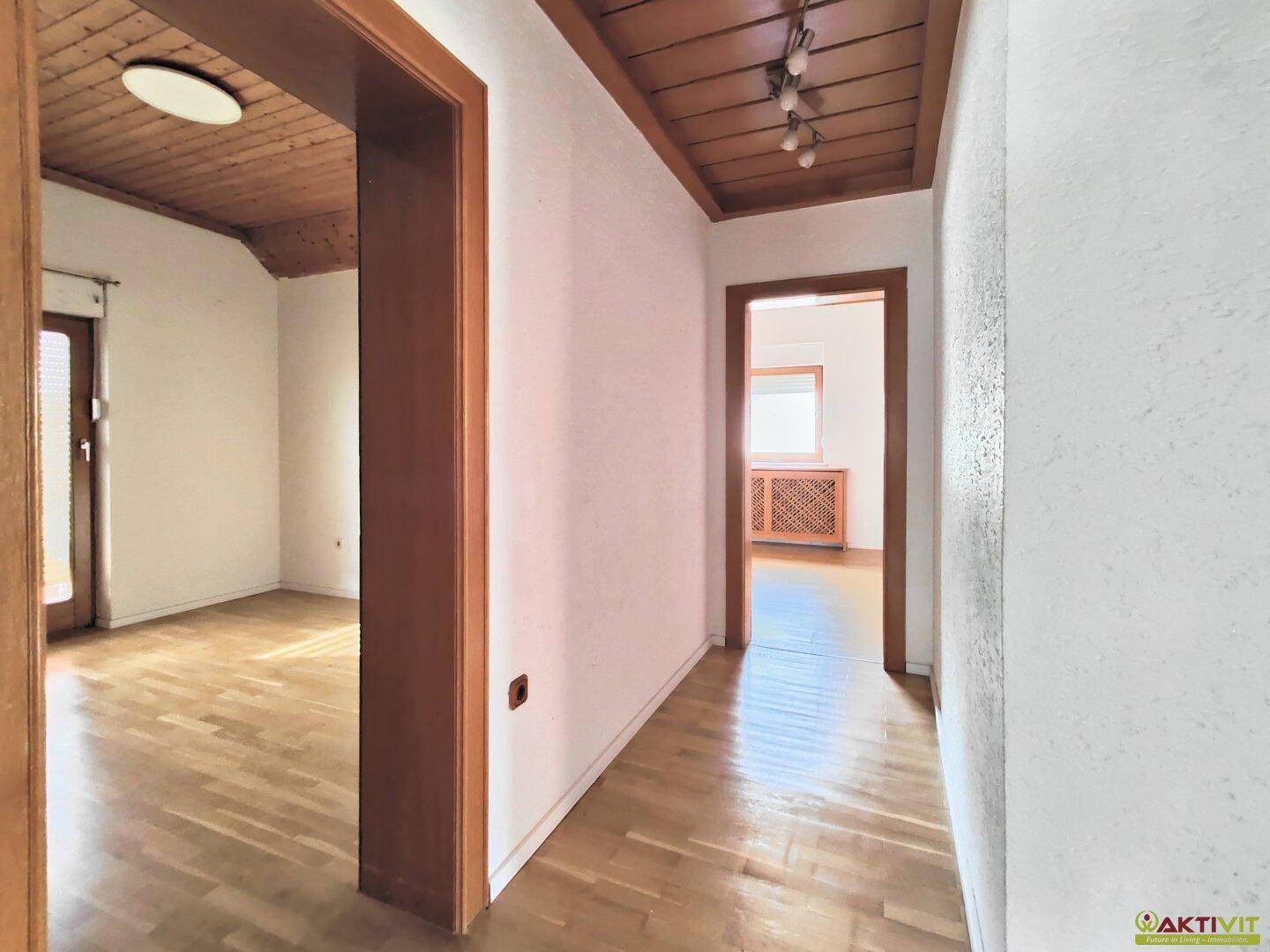 Heller Flur mit Holzdeckenverkleidung und Parkettboden, der zu weiteren Räumen führt.
