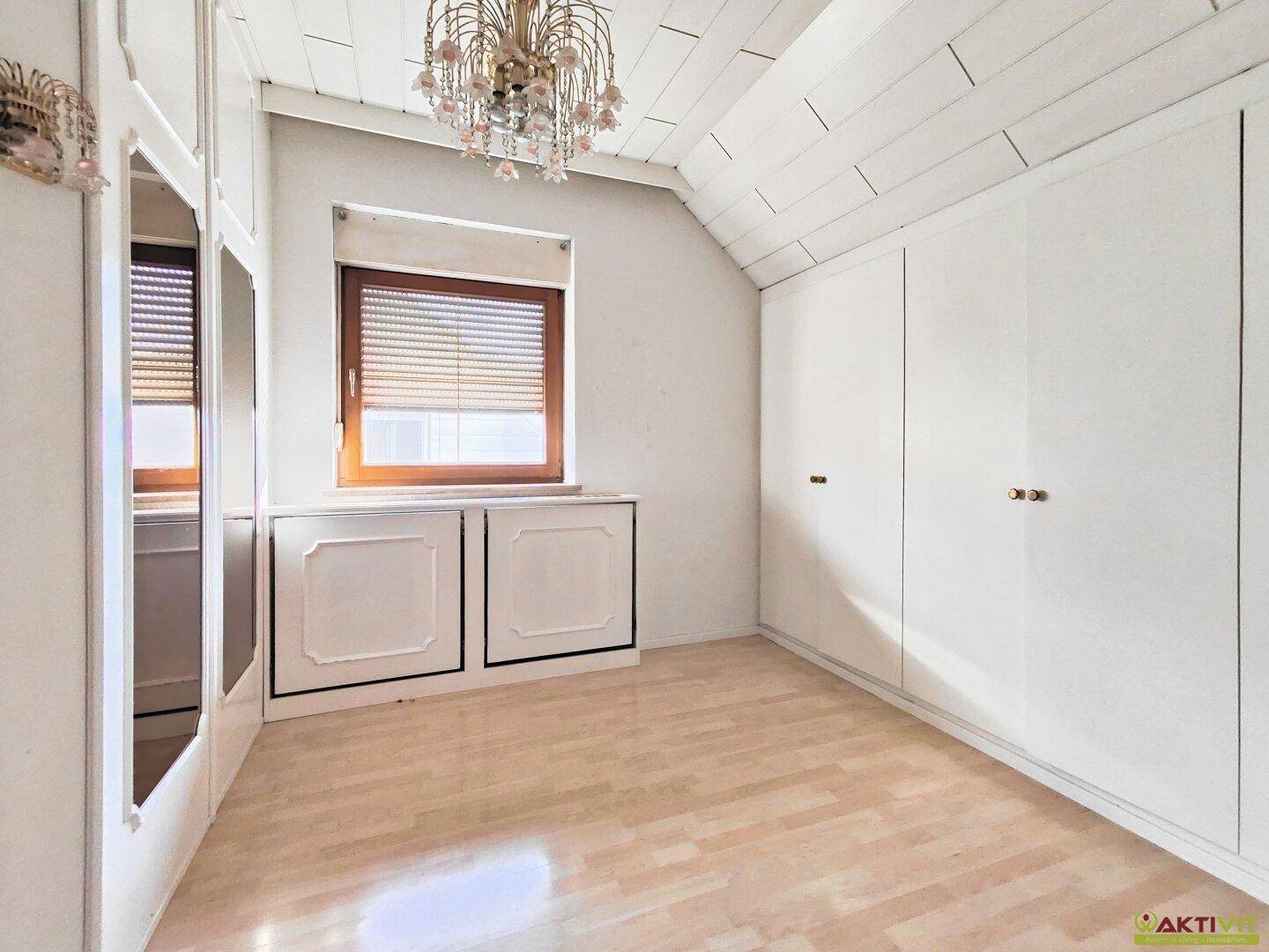 Kleines Zimmer mit weiß getäfelter Decke, Parkettboden und Einbauschränken.
