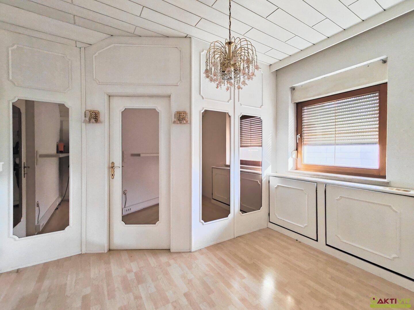 Zimmer mit weiß getäfelter Decke, Parkettboden und integrierten Spiegelschränken.