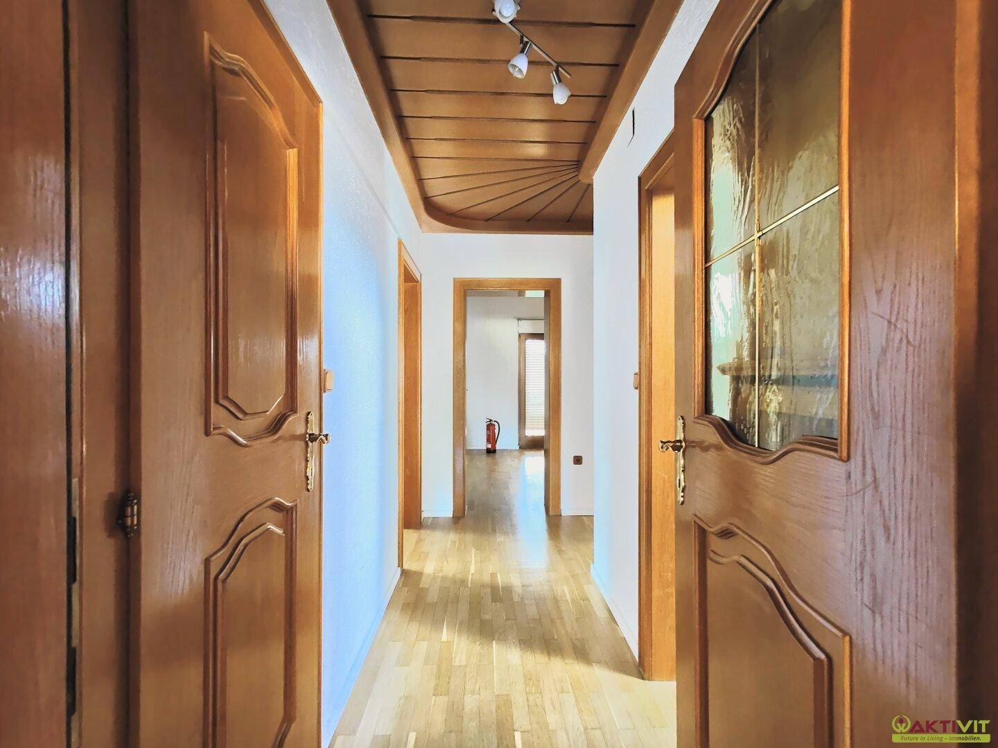Geräumiger Flur mit Holztüren und Holzdeckenverkleidung, der einen Blick in die Tiefe des Hauses bietet.