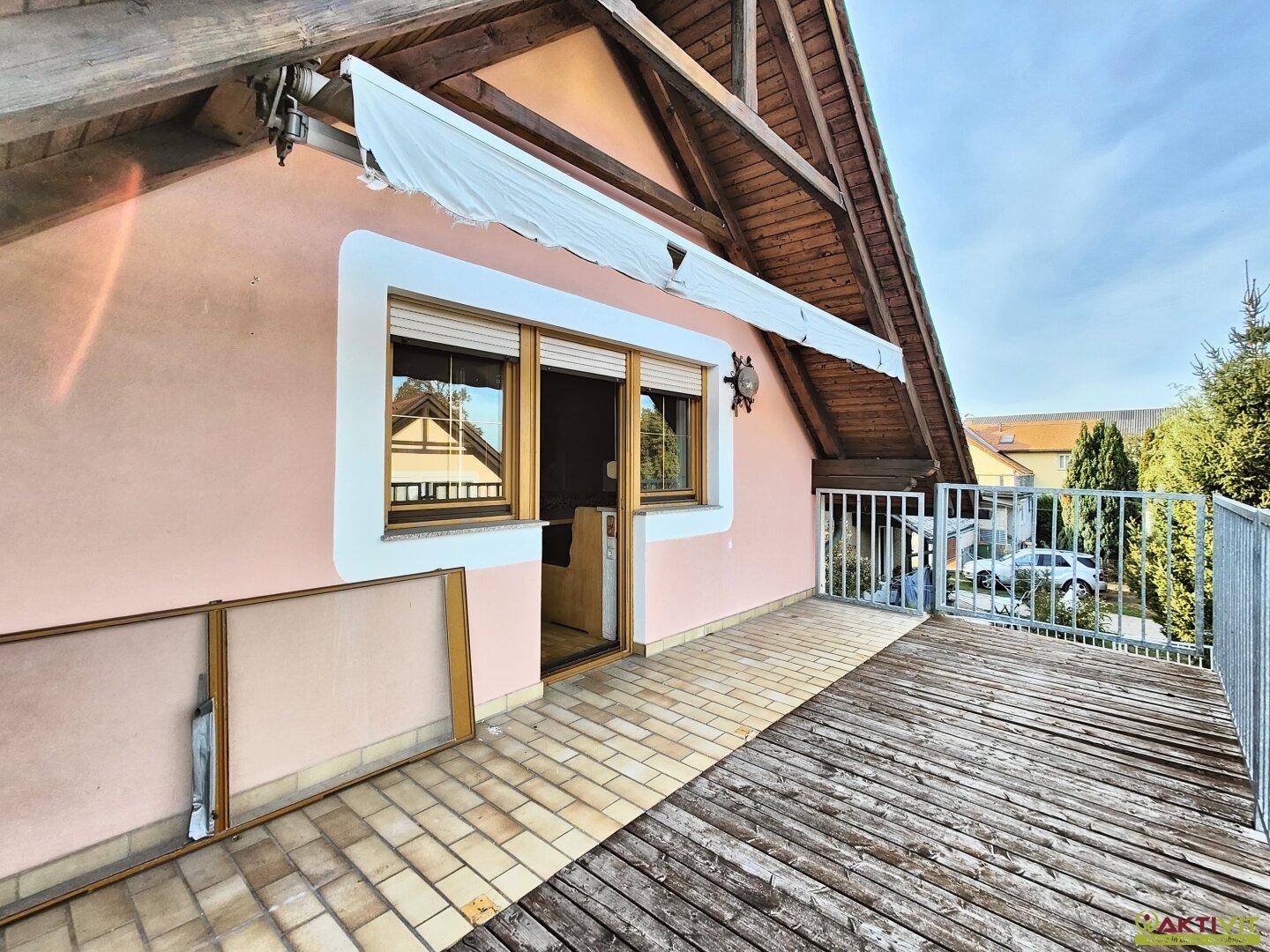 Geräumige Dachterrasse mit Holzboden und Markise, ideal für entspannte Stunden im Freien.