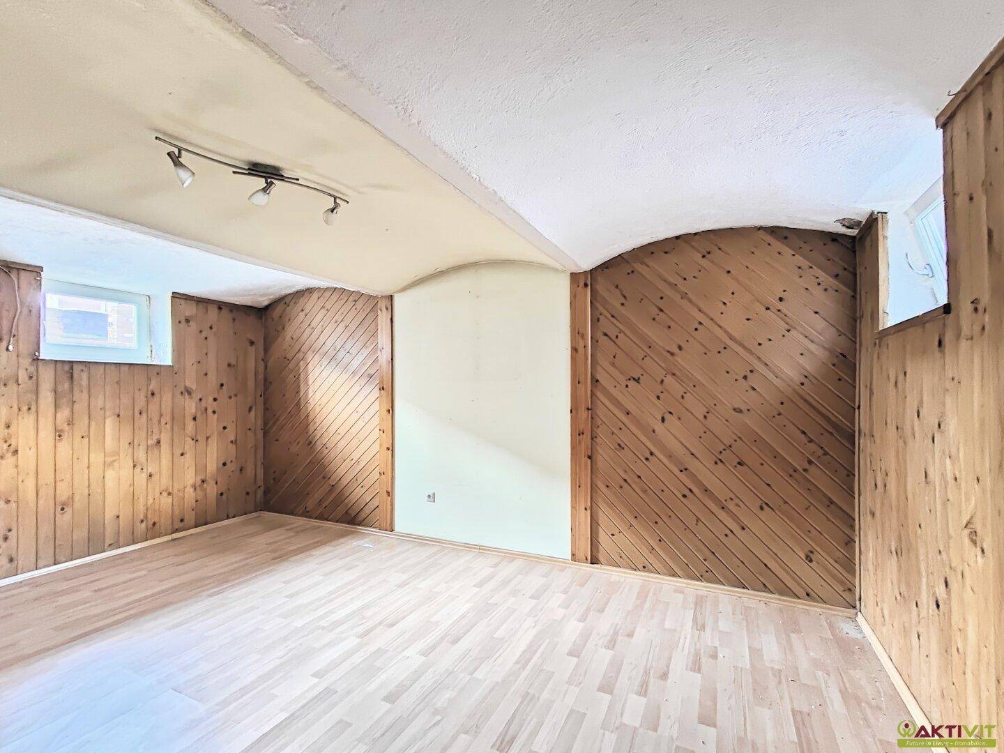 Geräumiger Kellerraum mit Holzwänden und Parkettboden, ideal für Lagerung oder Freizeitaktivitäten.