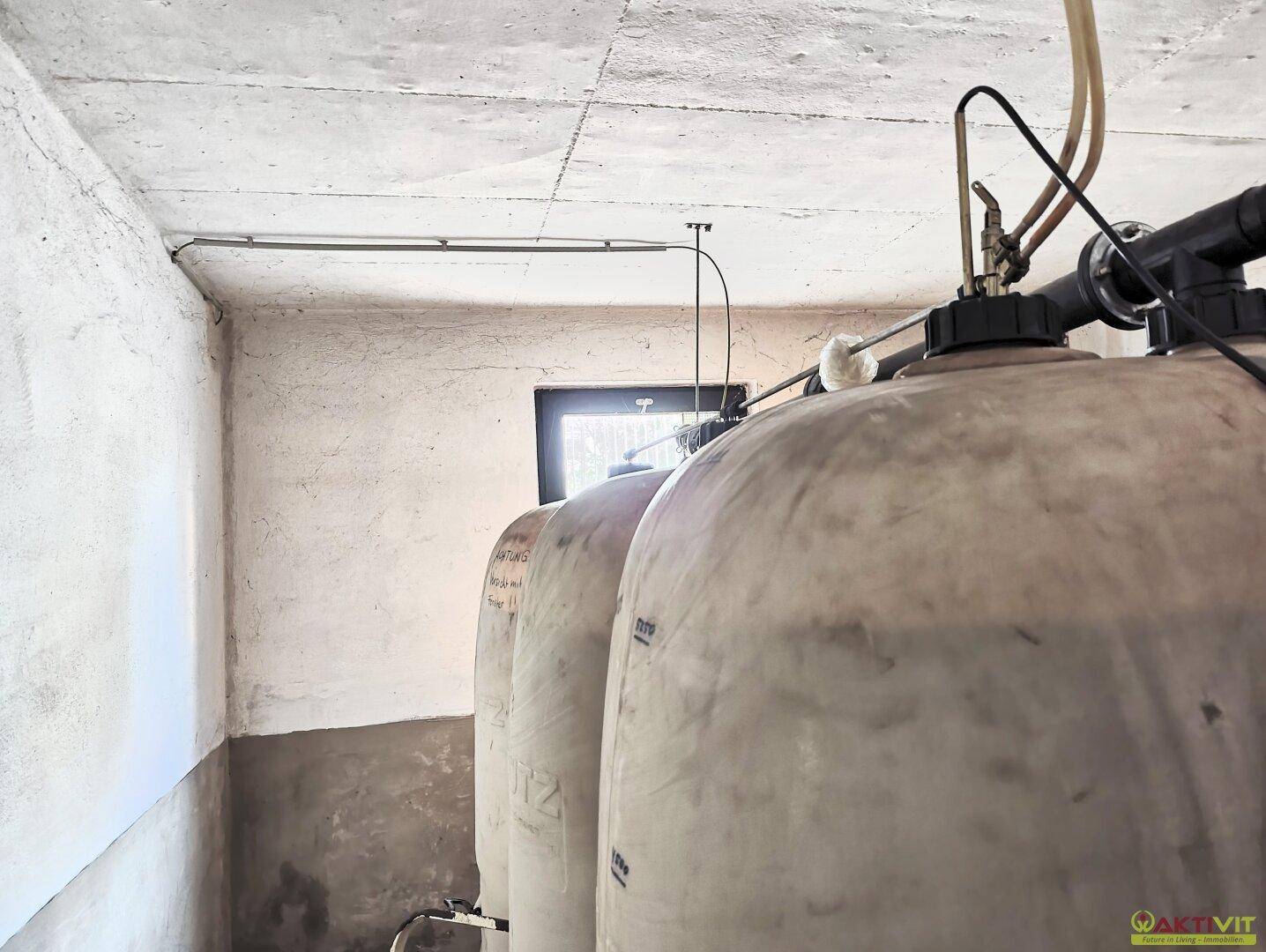 Kellerraum mit großen Speichertanks und einem kleinen Fenster, dient der Haustechnik.