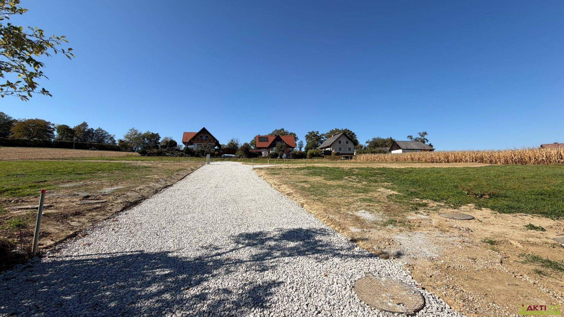 Zugehöriger Schotterweg auf dem Grundstück mit Blick auf die Nachbarschaft und Felder.