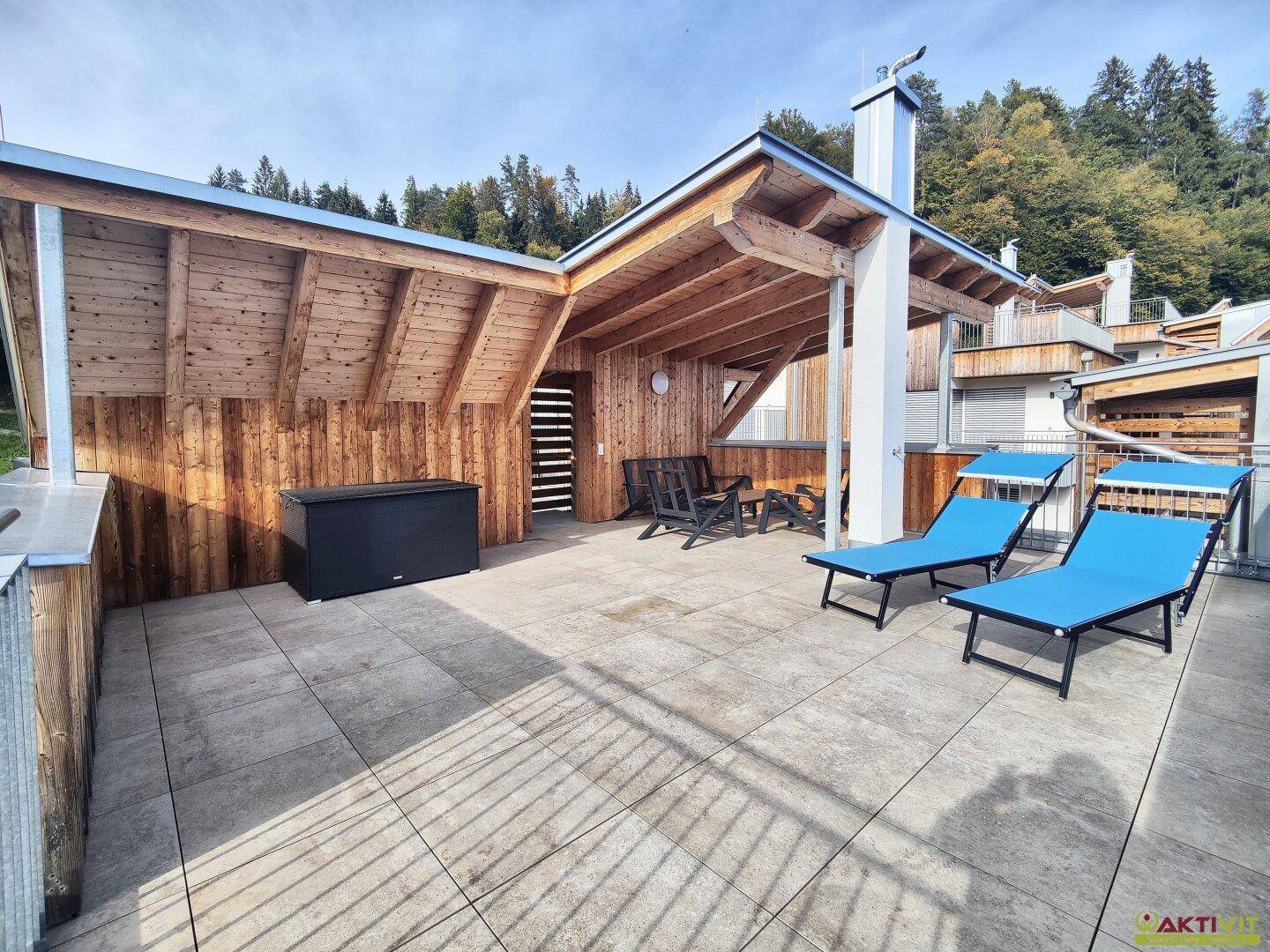 Große Dachterrasse mit Holzverkleidung, Sonnenliegen und viel Platz für Outdoor-Aktivitäten.